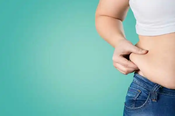 Image of woman pinching her love handles to show weight gain Holme Chapel